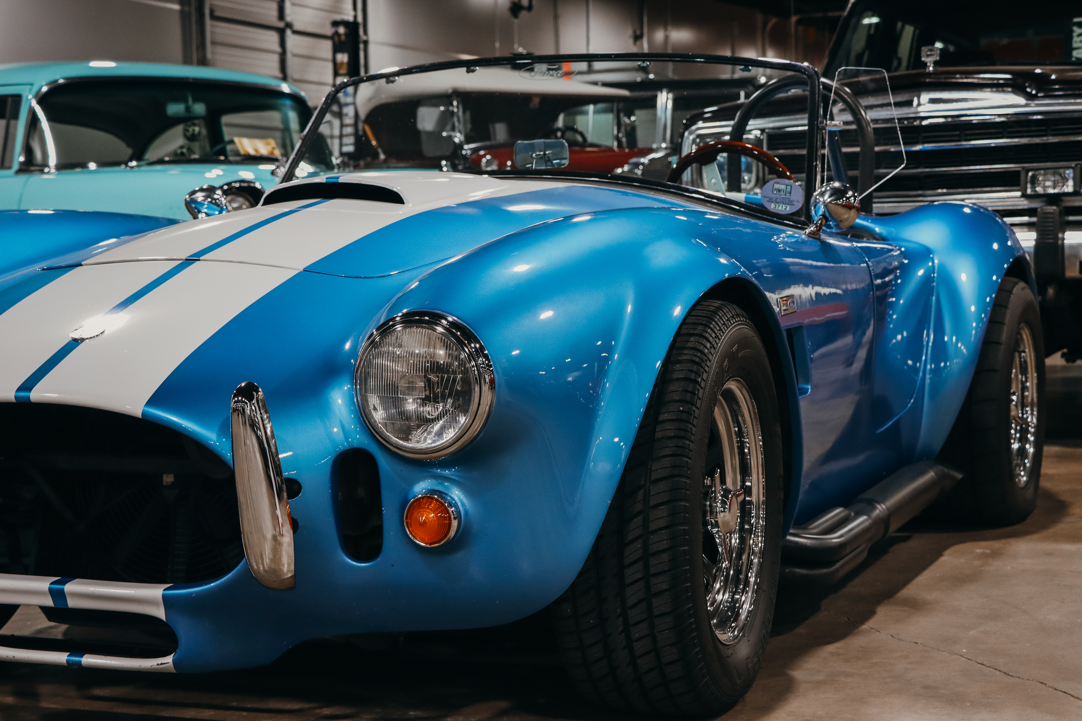 Blue and white classic car with a white stripe on a showroom floor.